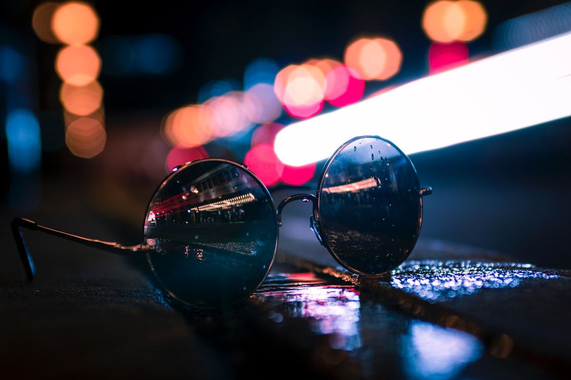Foto Sonnenbrille auf Straße in der Nacht mit bunter Beleuchtung - Fotocredit: Isaac Weatherly, pexels